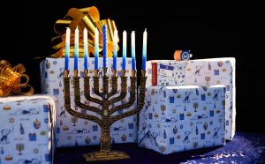 Menorah and candles in front of wrapped presents celebrating Hanukkah.