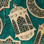Wooden cutout of Ramadan lantern against a royal green table.