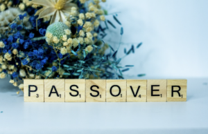 Bouquet of yellow and blue flowers with wooden squares spelling the word Passover.
