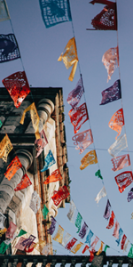 Multicolored flags flying above buildings in Valladolid, Mexico.