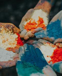 Hands full of different colored powders with palms up in a circle.