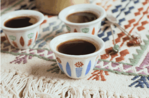 Arabic coffee cups on a patterned tapestry rug.
