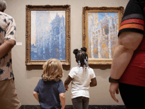 Two children looking at art on a wall with adults on either side.