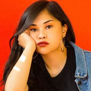 Ruby Ibarra in front of a red background, leaning on her right elbow.