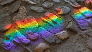 Rainbow reflection on top of gray rocks.
