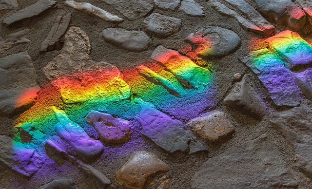 Rainbow reflection on top of gray rocks.