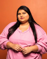 Indigenous playwright Tara Moses standing in front of a plain orange background