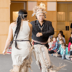 A Native American man and woman doing a native dance, dancing in a circle.