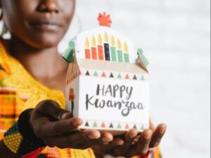 A Kwanzaa kinara with three red candles on the left, a single black candle in the center, and three green candles on the right.