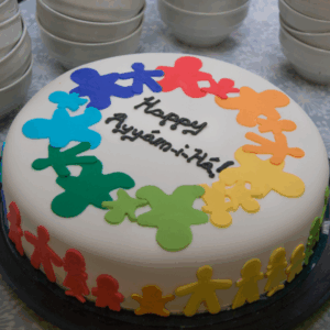 A white cake with rainbow people and the words "Ayyám-i-Há" in icing.
