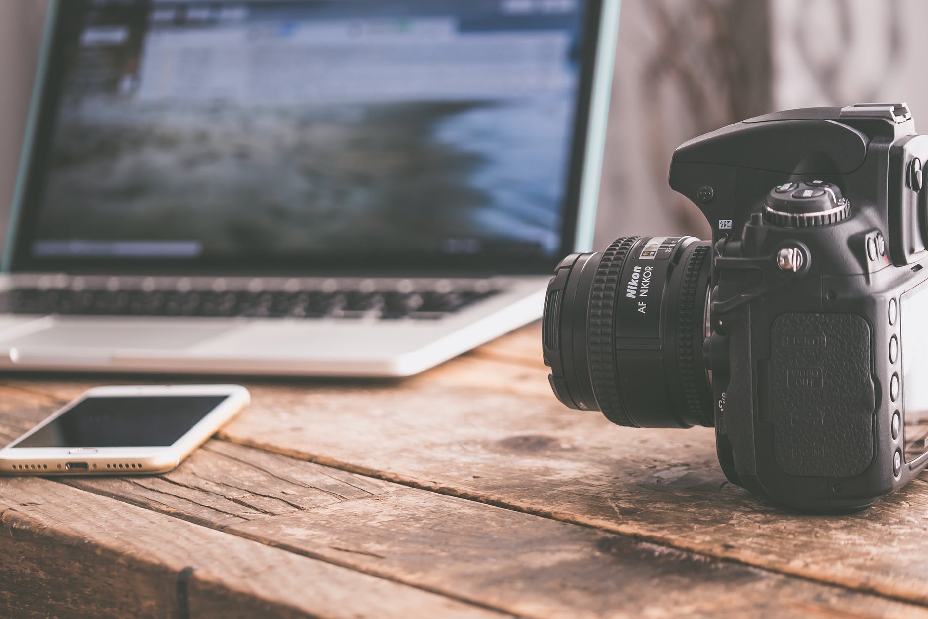 A camera next to an iphone and laptop.