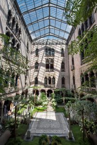 The Isabella Stewart Gardner museum courtyard, full of greenery and a glass ceiling 