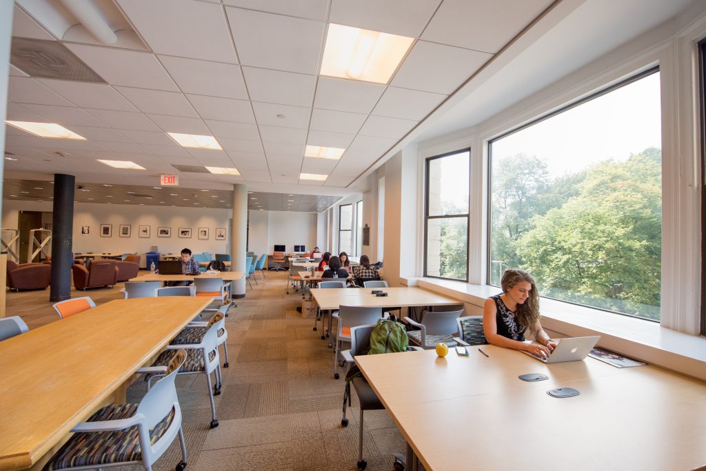 Students working on laptops in the Iwasaki Library, with windows overlooking the Common, it's a great place to study. 