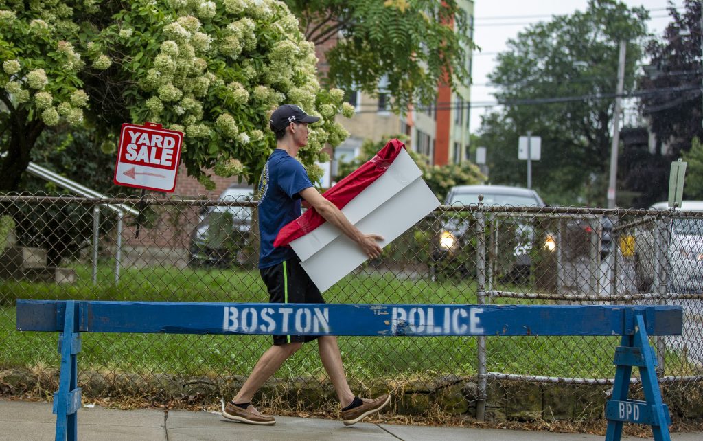 A man carries a box down Ashford Street in Allston on moving day. (Jesse Costa/WBUR)