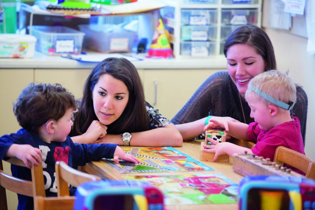 Two of Emerson's aspiring SLP students working with two young children in the classroom. 
