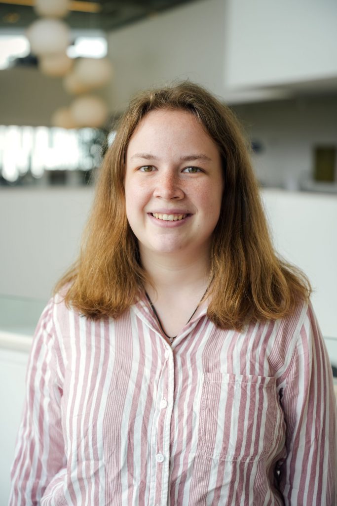 Abby Velletri in striped pink shirt, smiling at camera
