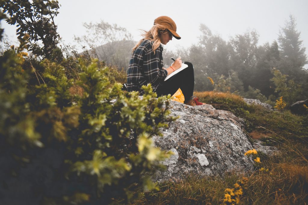 Grad school applicant sits outdoors and journals