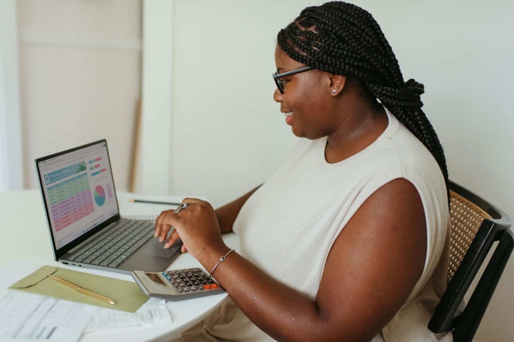 A woman works at her laptop with a calculator after changing careers