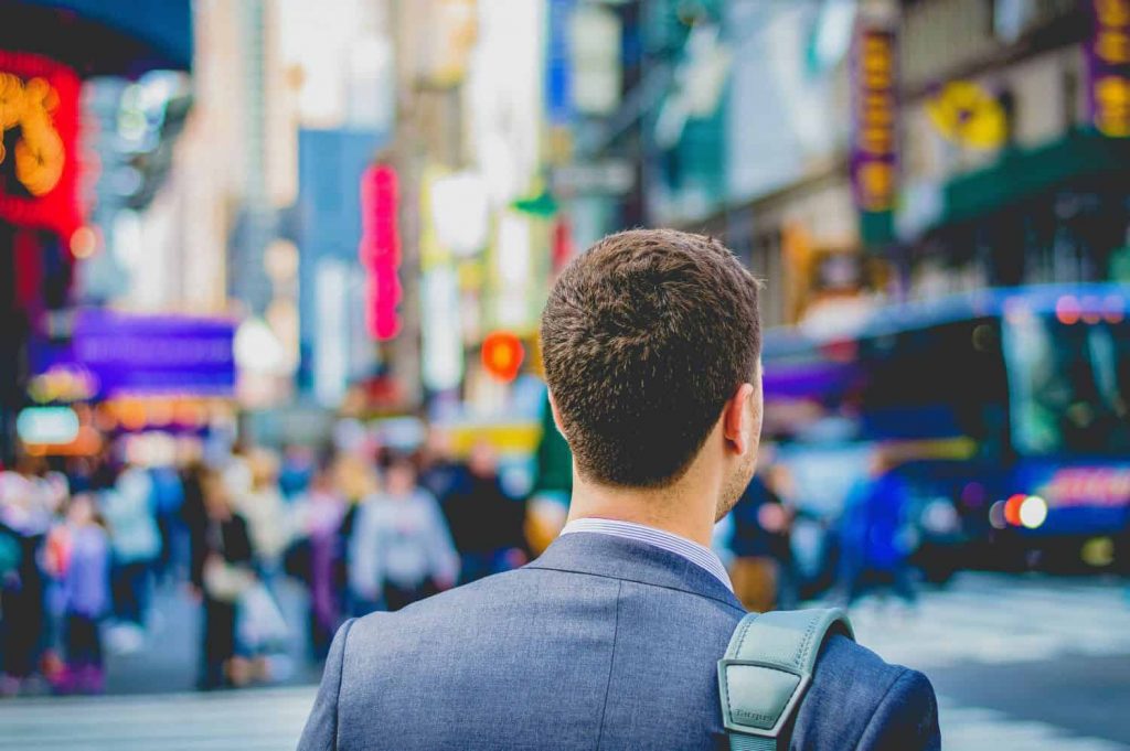 Young man walks in a crowded city after a career change