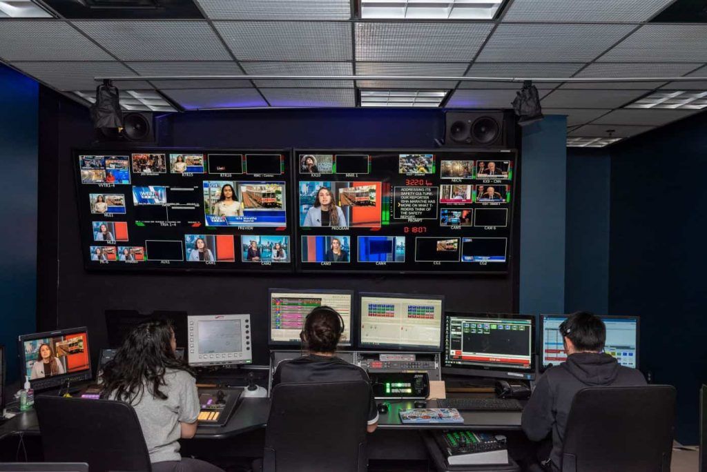 Students working at a wall full of screens in the Journalism Production Center