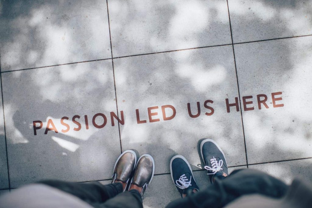 People standing over pavement art that says "Passion led us here"