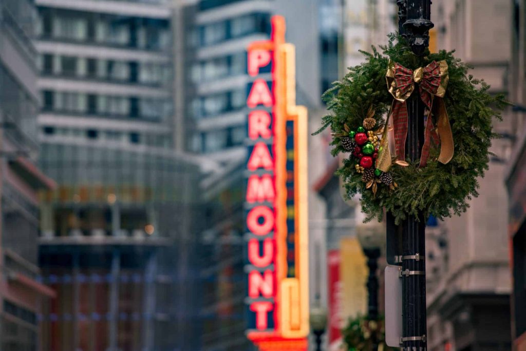 A holiday wreath hanging from a lamp post, with the Paramount theater sign in the background