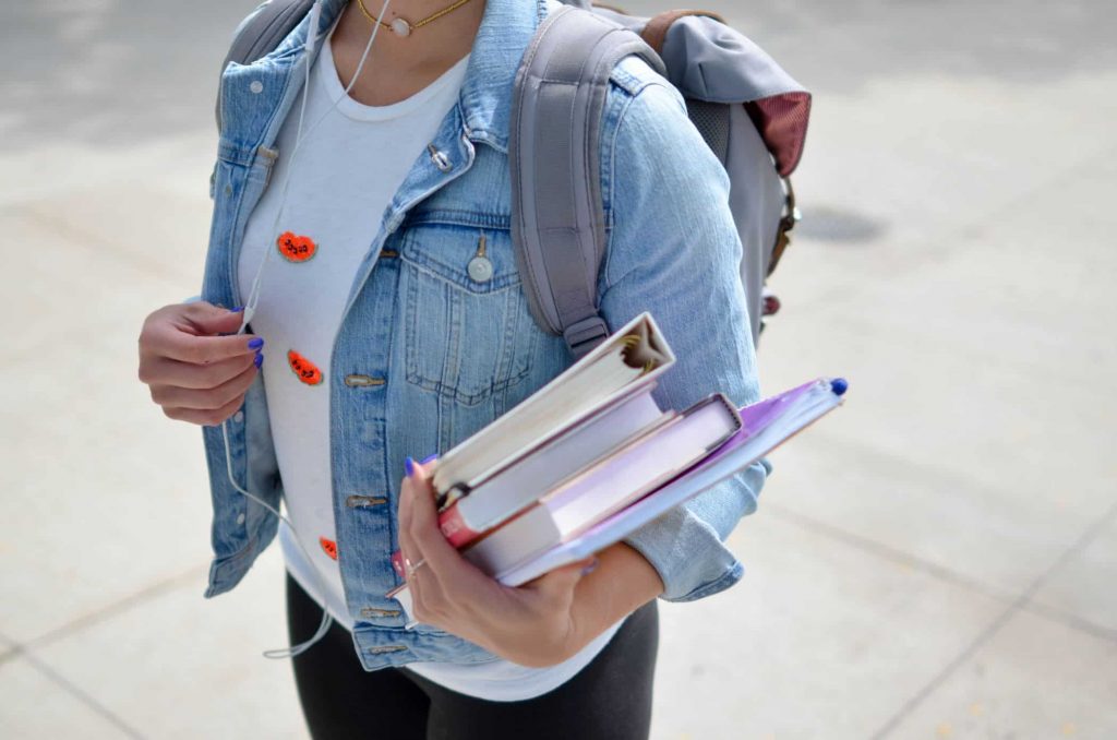 Graduate student walks around campus with textbooks