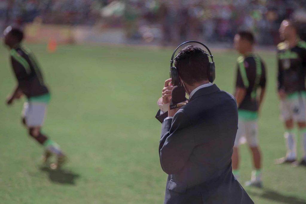 Sports reporter watches as a team plays soccer