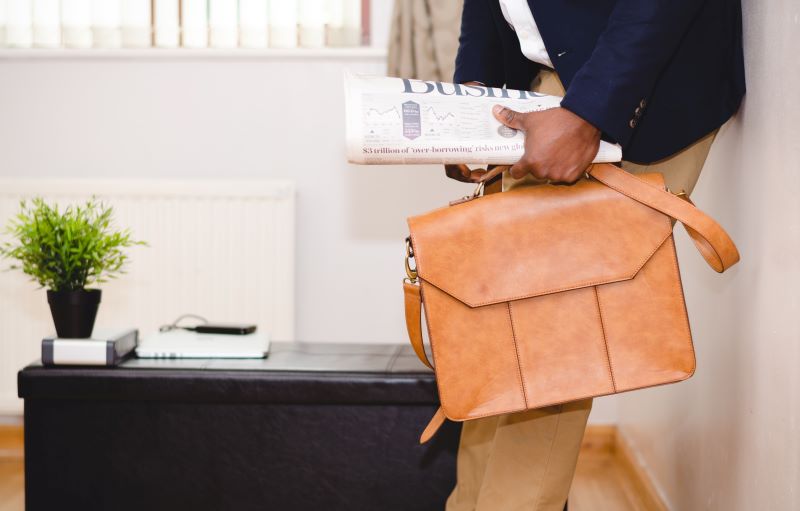 Graduate student holding a brief case and newspaper in an office