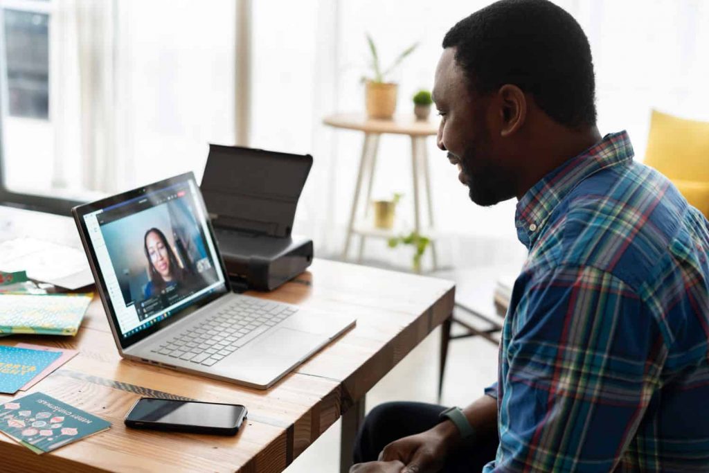 A graduate student sitting at a laptop, having a Zoom meeting