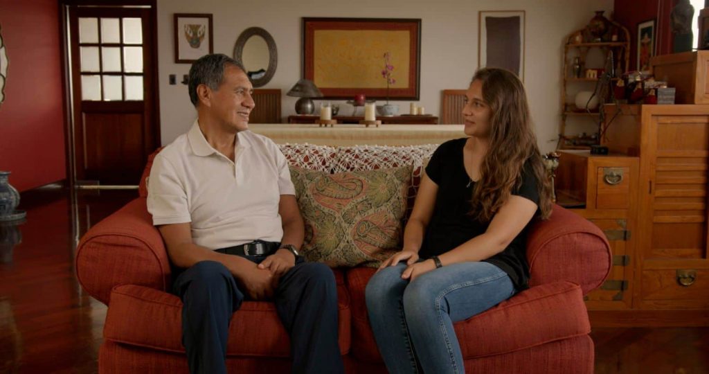 Isabel and her father sitting on a couch 