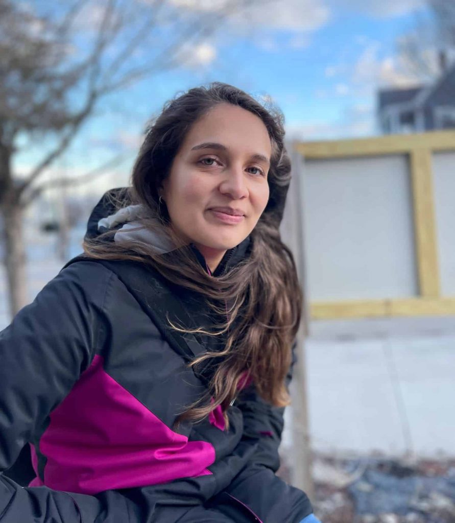 Isabel Miranda, sitting outside with trees and buildings behind her