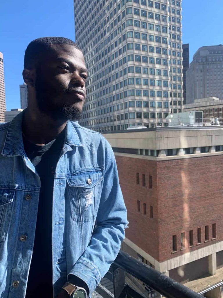 Olu Adeleye standing on a rooftop, with city buildings in the background