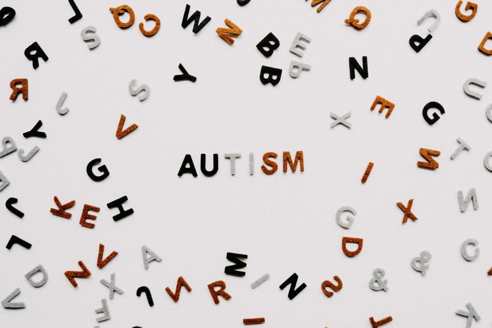 A white background with letters scattered throughout, with the word  "Autism" spelled in the center