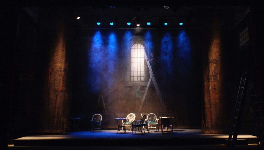 An empty theater stage set with chairs and tables