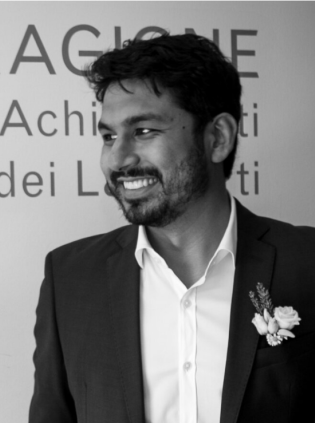 Alex Nezam smiling and wearing a suit in a black and white picture