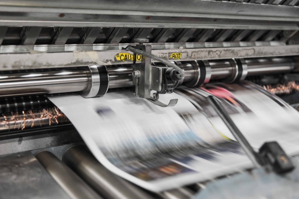 A newspaper running through an industrial printer