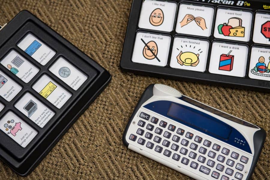 Three alternative and augmentative communication devices that Communication Disorders students learn to operate while in the program. One device has a keyboard for text-to-speech use, and the other two devices have icons and text in a grid.