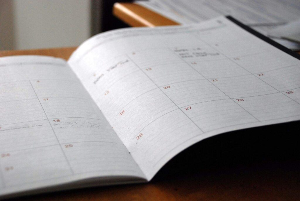 A monthly calendar or planner sits open on a table