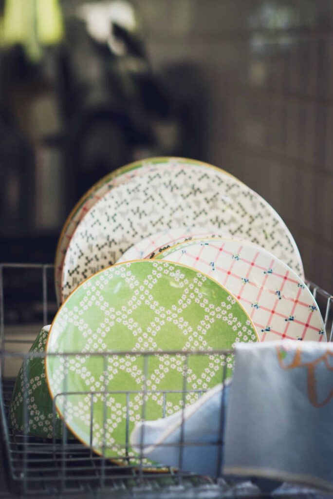 Plates of different sizes and collors stacked in a drying rack