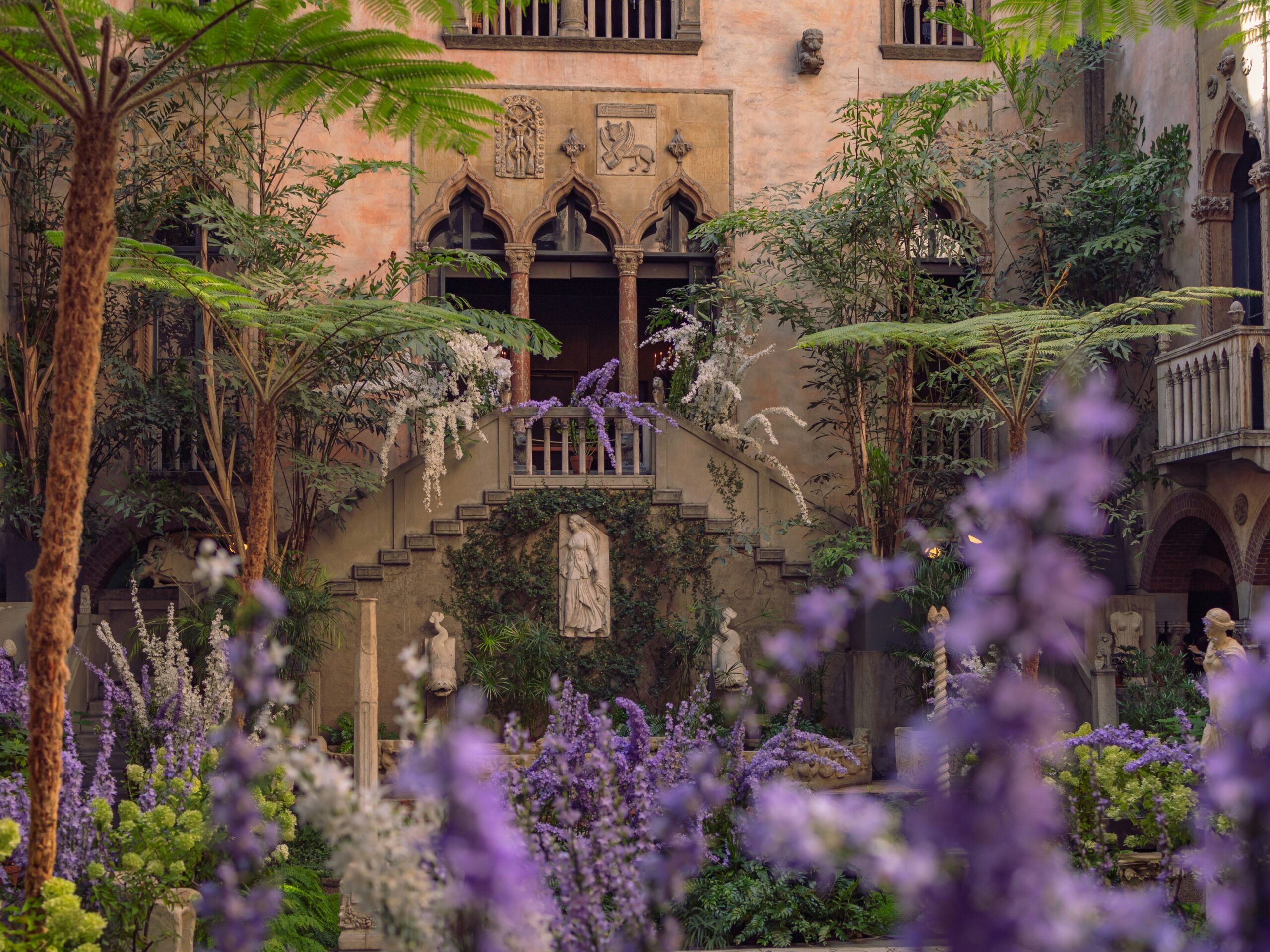 Picture of the Isabella Stewart Gardner Museum courtyard at dusk featuring trees and flowers.