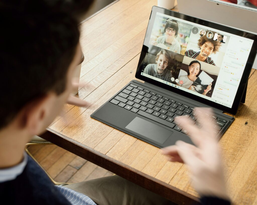 Man on a Zoom call on his computer with four other participants.