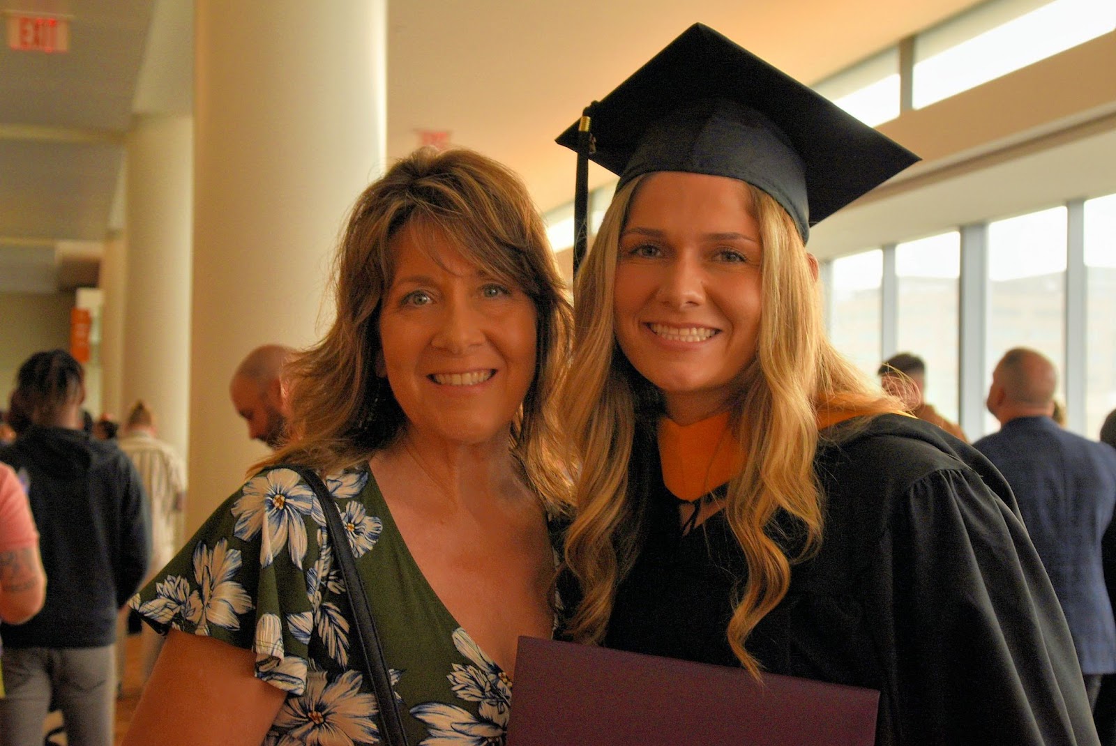 Mother and daughter (the graduate) embrace with a smile.