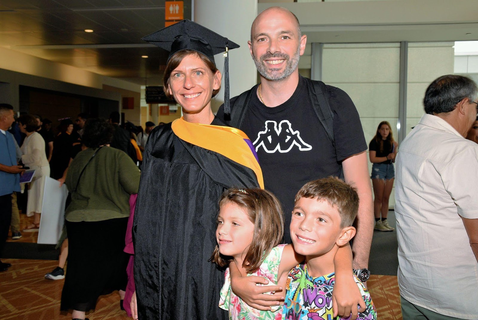 A family with a husband and two kids celebrate their mother/wife who just graduated.