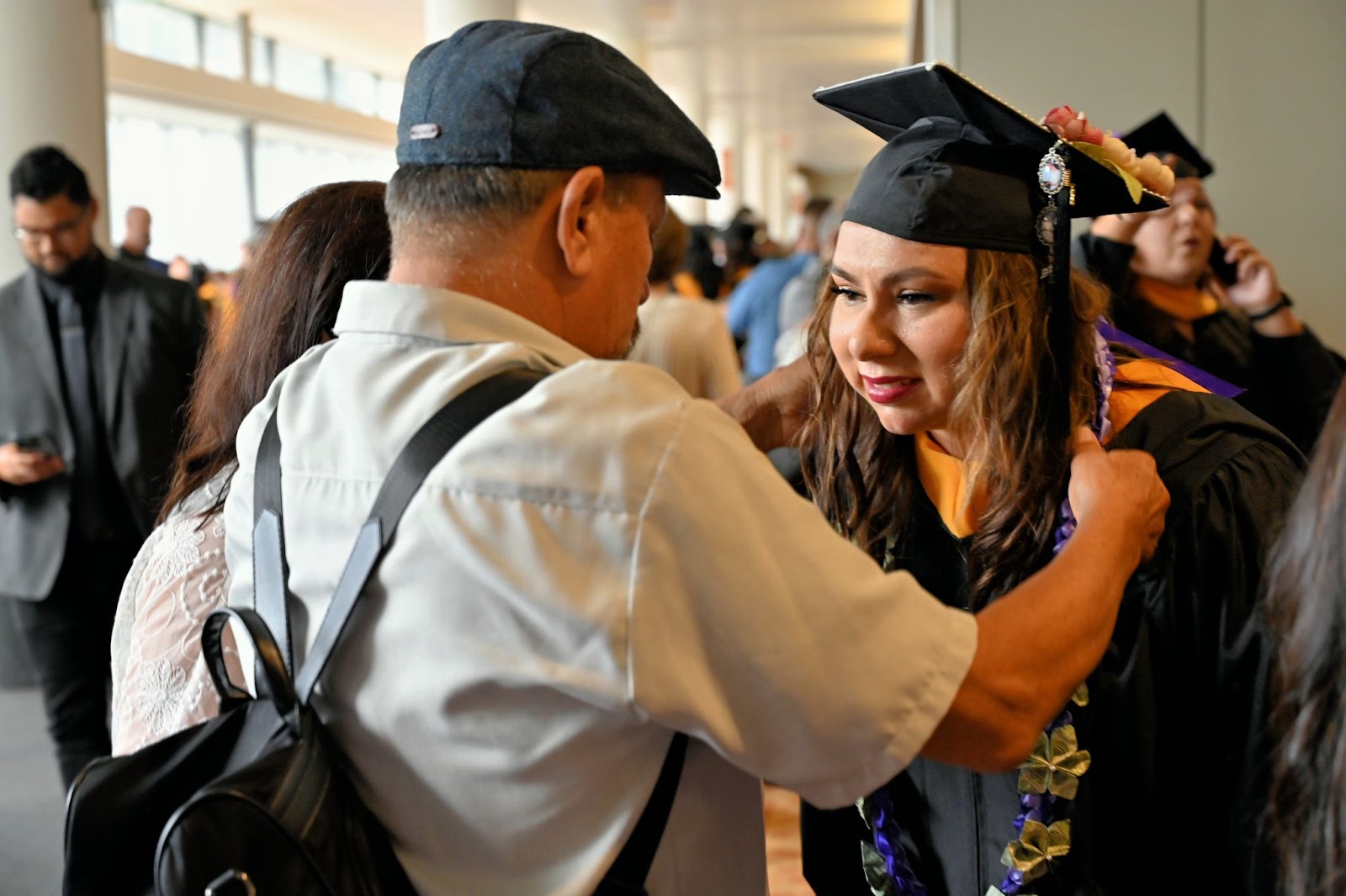 A family member crowns their graduate with special regalia to wear over her head.