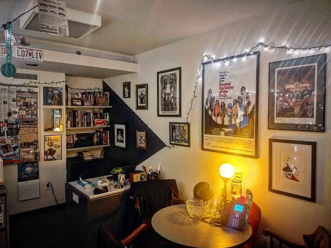 Katherine's office and workspace, including a desk, ambient lighting, and multiple film-related posters on the wall with a bookshelf in the back.