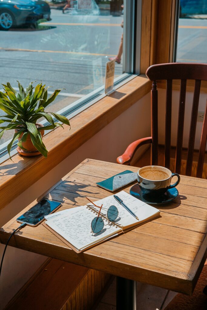 Table in a cafe next to a window, covered with a cup of cof