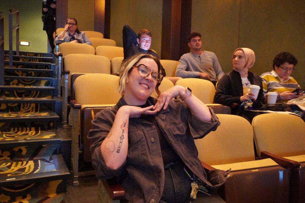 A student smiles at the camera from her seat during orientation.