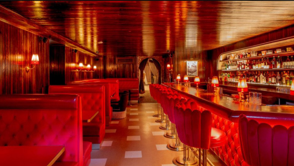 Interior of the Red Fox, with a bar and booths in red lighting.