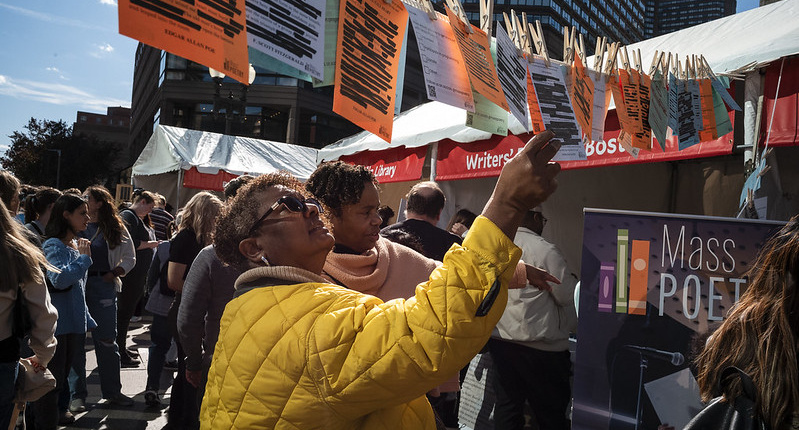 Two women look at colorful pages of blackout poetry that are hanging up at the Boston Book Festival.